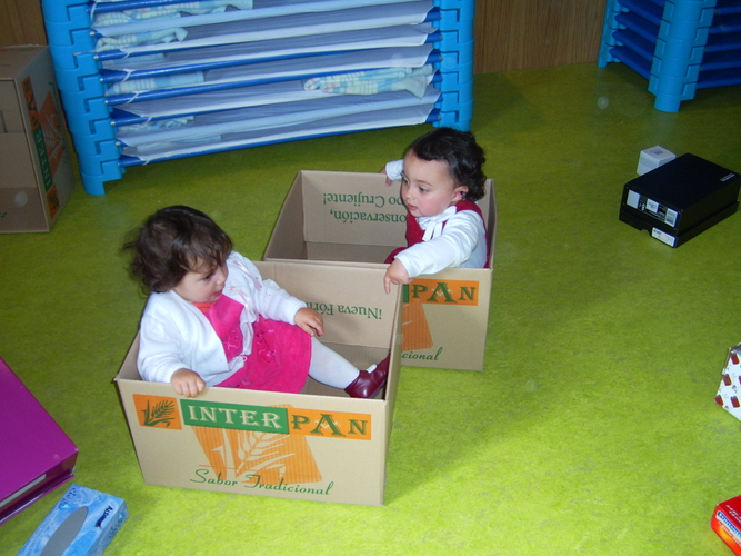 Niñas pequeñas metidas en unas cajas de cartón.