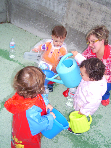 Niños junto a su profesora, utilizando regaderas.