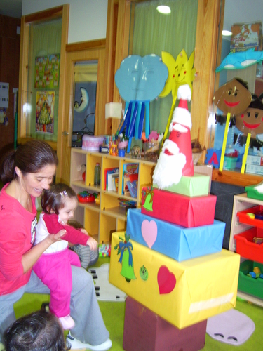 Profesora con niña muy pequeño decorando unos regalos.