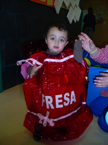 Niña muy pequeña disfrazada de caramelo de fresa.