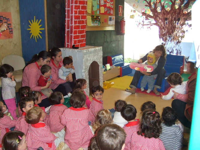 Profesora leyendo un libro para un grupo de niños y otras profesoras.