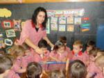 Educadora junto a los niños observando el tanque con colorante