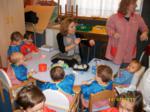 Una madre y una educadora pintando adornos junto a los niños