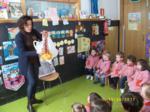 Una conferenciante preparandose para una lectura ante la mirada de los niños sentados en corro