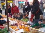 Madres y niños en un puesto de frutas