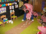 Nino ayudado por una educadora, marcando sus pisadas en una alfombra de papel