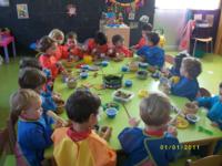 Niños dentro del aula, sentados alrededor de una mesa realizando actividadades manuales