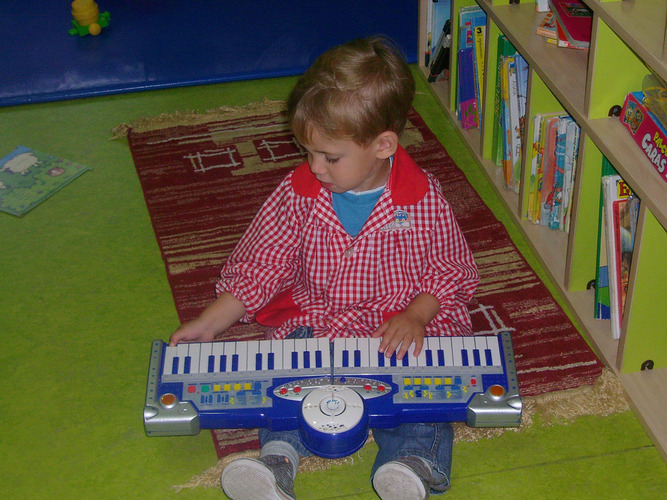 Niño rubio tocando un teclado.