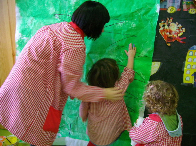 Niños y su profesora pintando un mural.