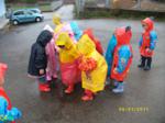 Varios niños bajo la lluvia protegidos por chubasqueros de colores
