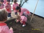 Educadora plantando, con la ayuda de un niño