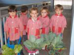 Niños con sus carretillas, mostrando las verduras del huerto