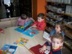 Niños sentados en una mesa redonda trabajando con libros